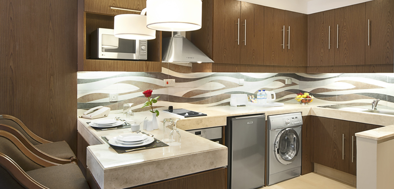 kitchen with microwave, fridge, freezer, dishwasher, toaster and kettle for tea and coffee at Oaks Liwa Executive Suites hotel in Abu Dhabi, United Arab Emirates